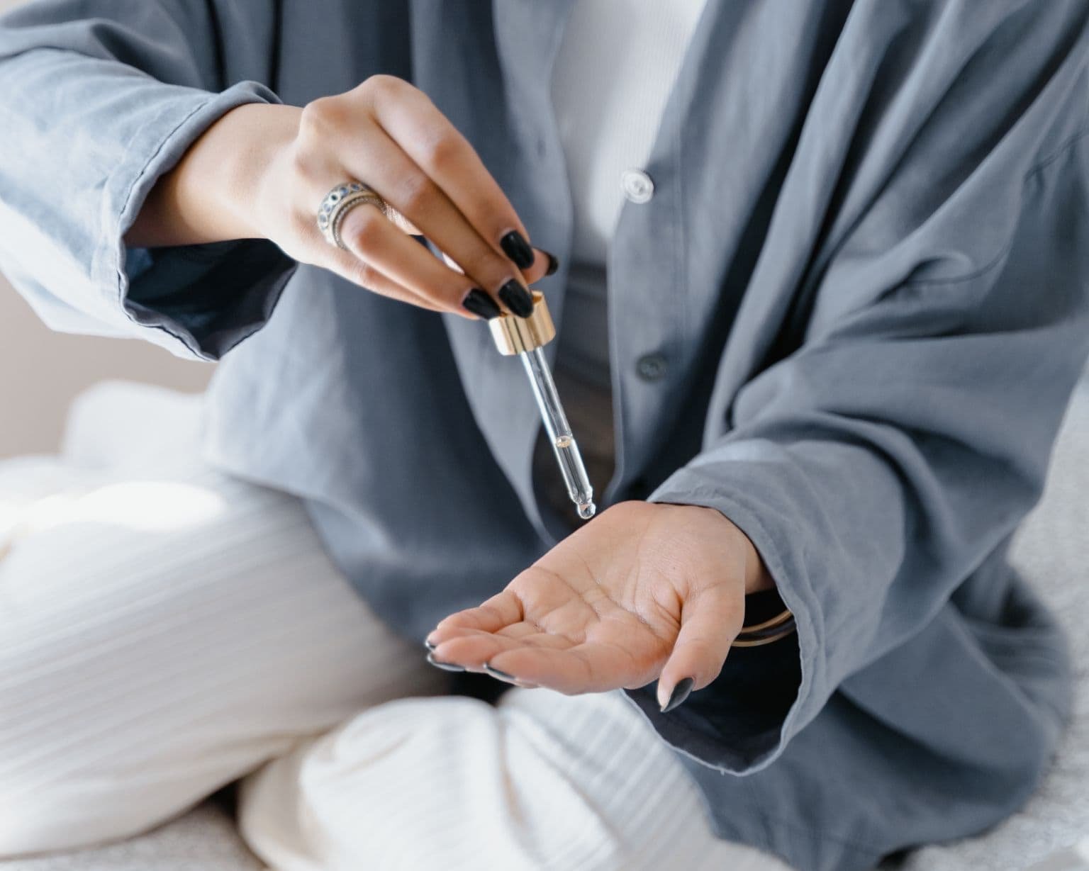 Mujer aplicando aceite en la mano con un gotero, representa bienestar, equilibrio hormonal y autocuidado femenino con aceites esenciales – Un Aceite Para Eso