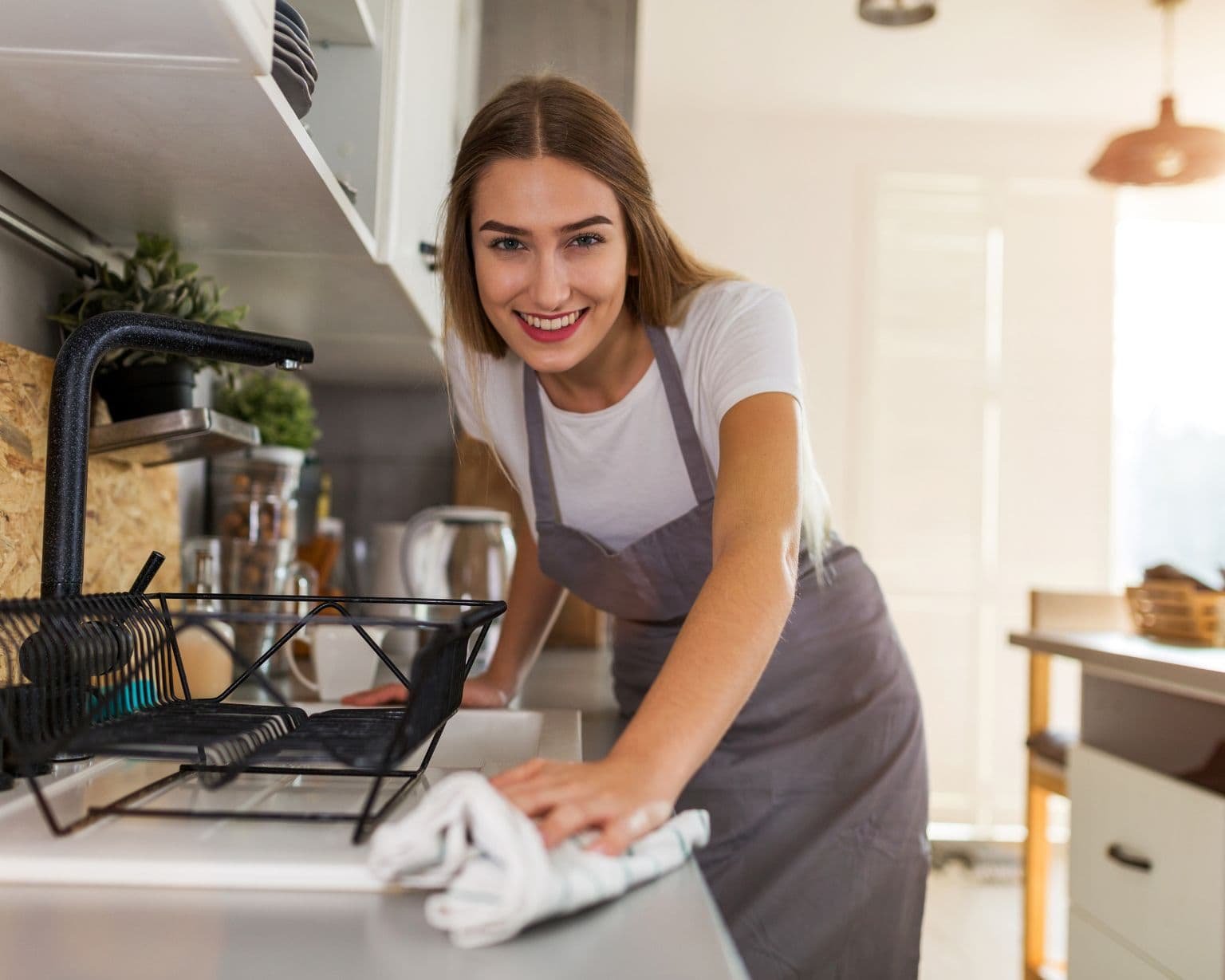Mamá limpiando la cocina con un limpiador natural en botella de vidrio, representa limpieza segura y ecológica con aceites esenciales – Un Aceite Para Eso