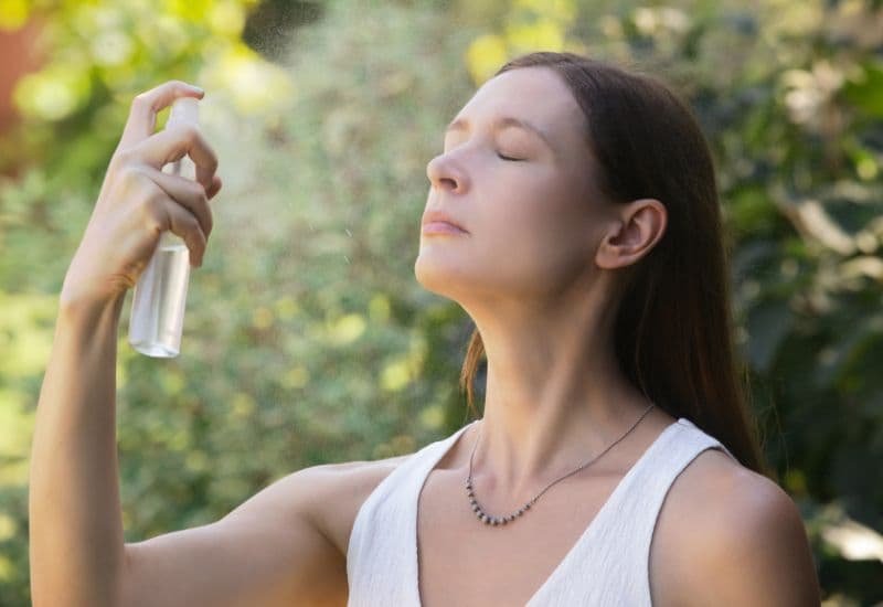 Mujer aplicando un mist facial en medio de la naturaleza, representa frescura, conexión y bienestar con aceites esenciales – Un Aceite Para Eso