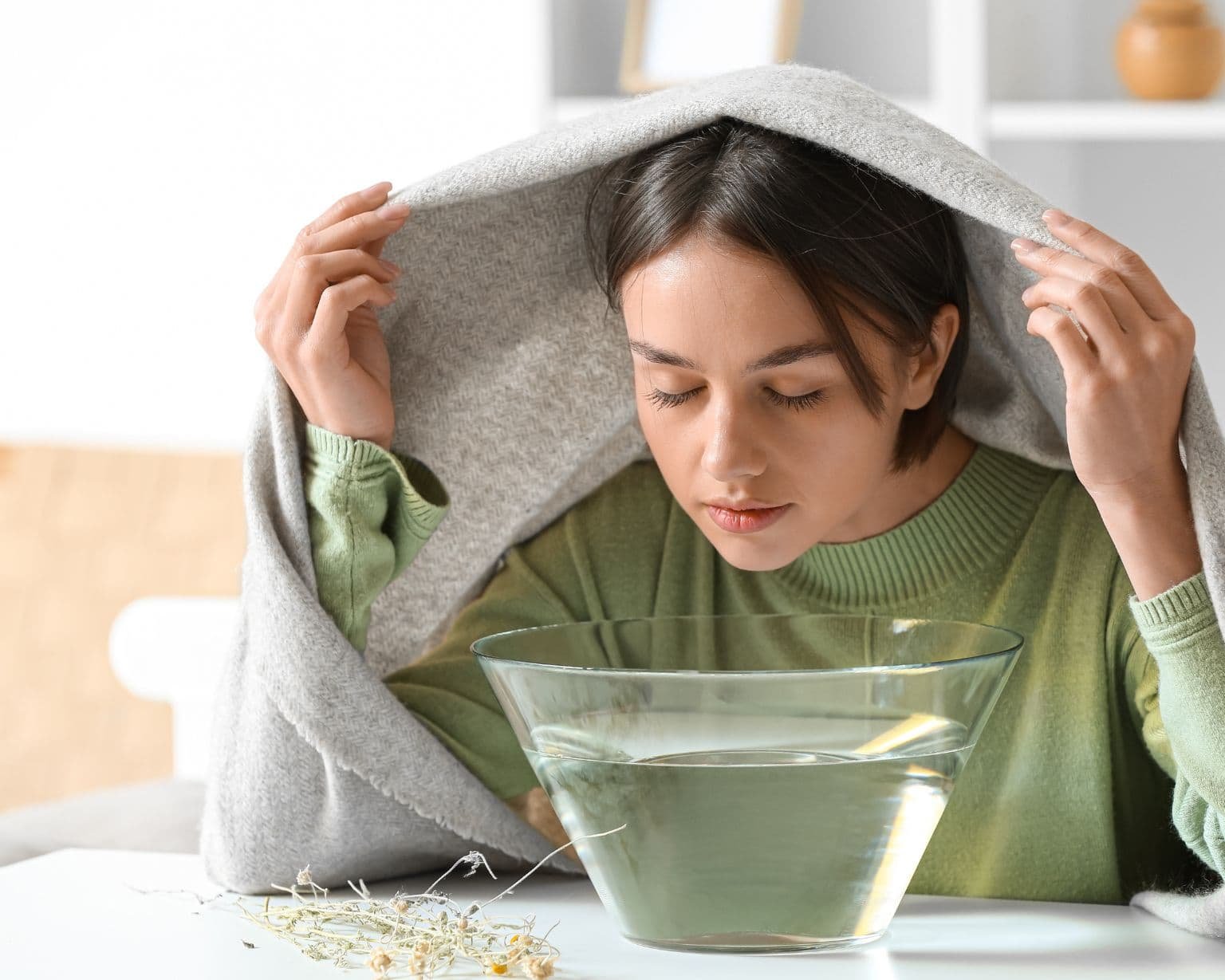 Joven haciendo vaporización con toalla sobre la cabeza y vapor subiendo del recipiente, representa alivio natural de la congestión con aceites esenciales – Un Aceite Para Eso.