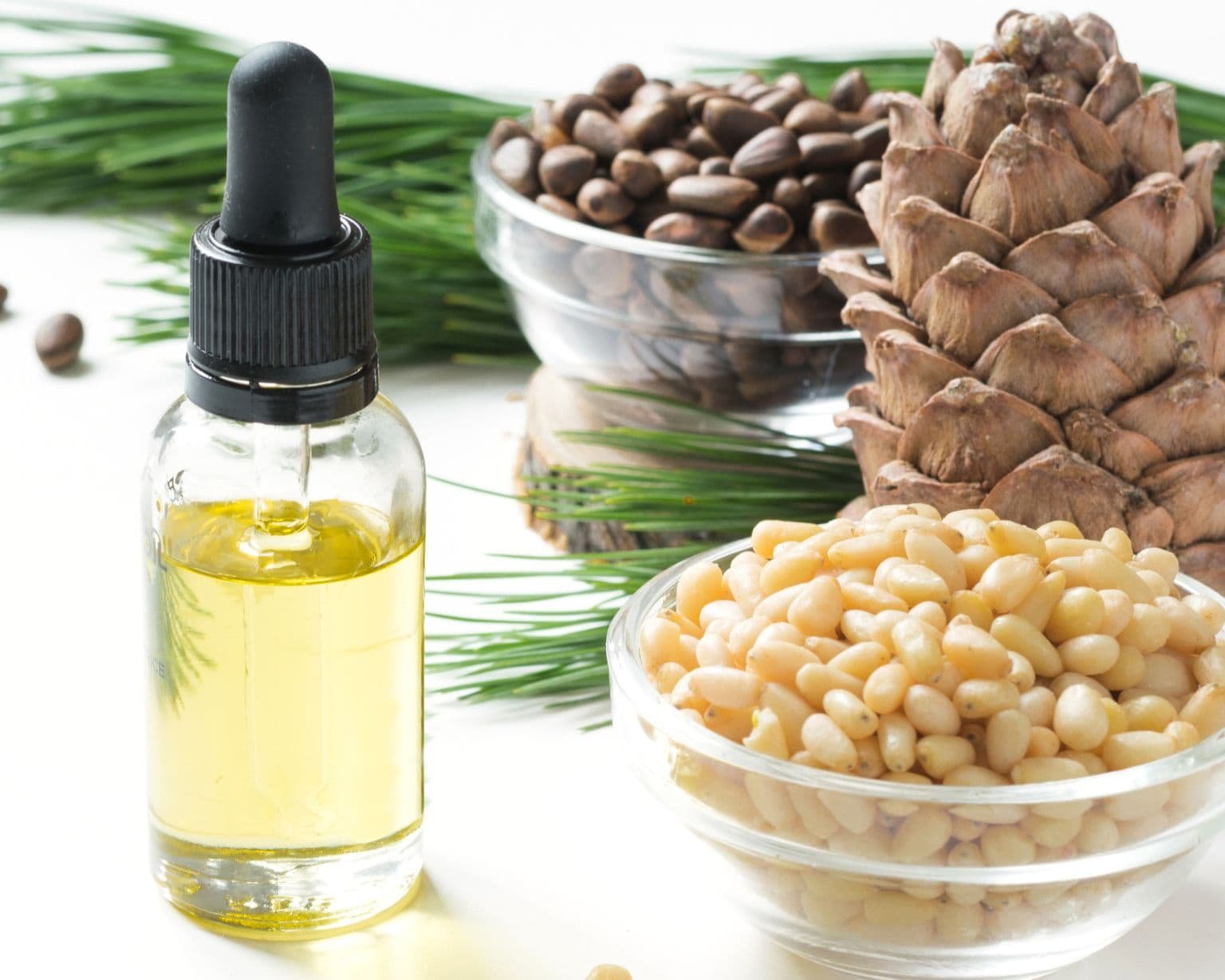 aceite esencial de cedro en frasco con ramas y semillas de cedro sobre fondo claro