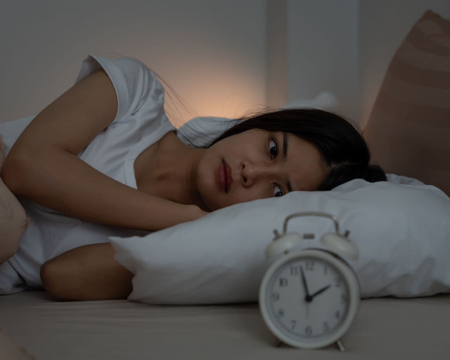 mamá despierta en la cama por la noche usando aceites esenciales para dormir