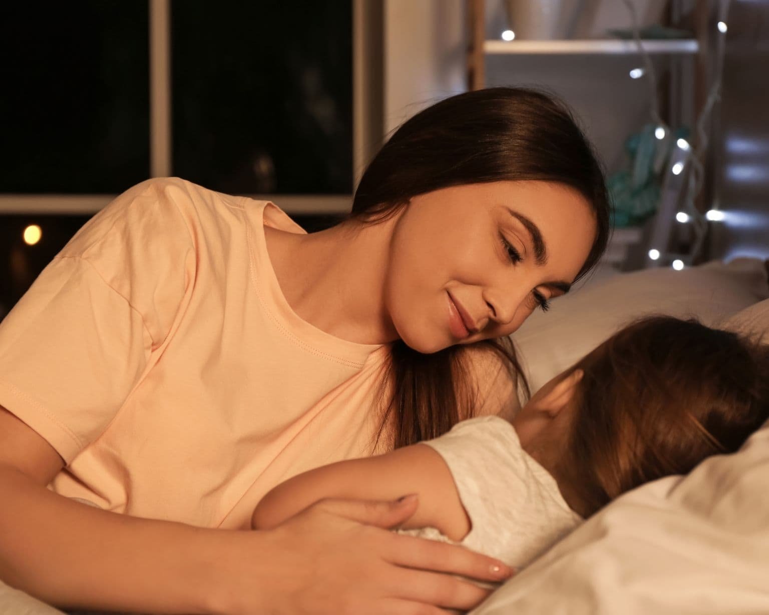 mamá acompañando a su hija a dormir en una rutina nocturna tranquila